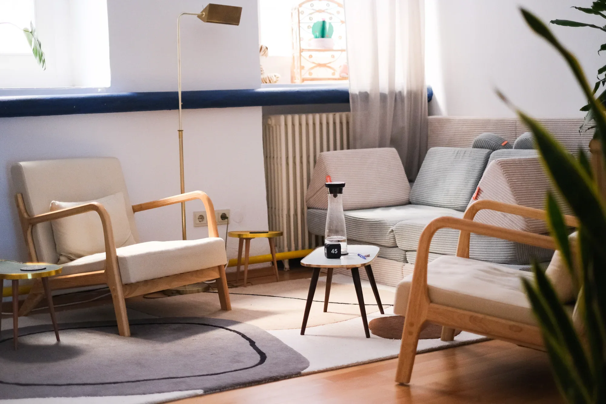 Heller Therapieraum mit bequemen Sesseln, Sofa und Pflanzen.